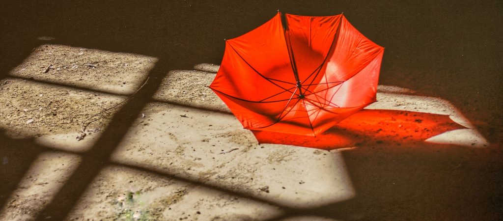 A red umbrella lying in sand