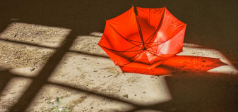 A red umbrella lying in sand