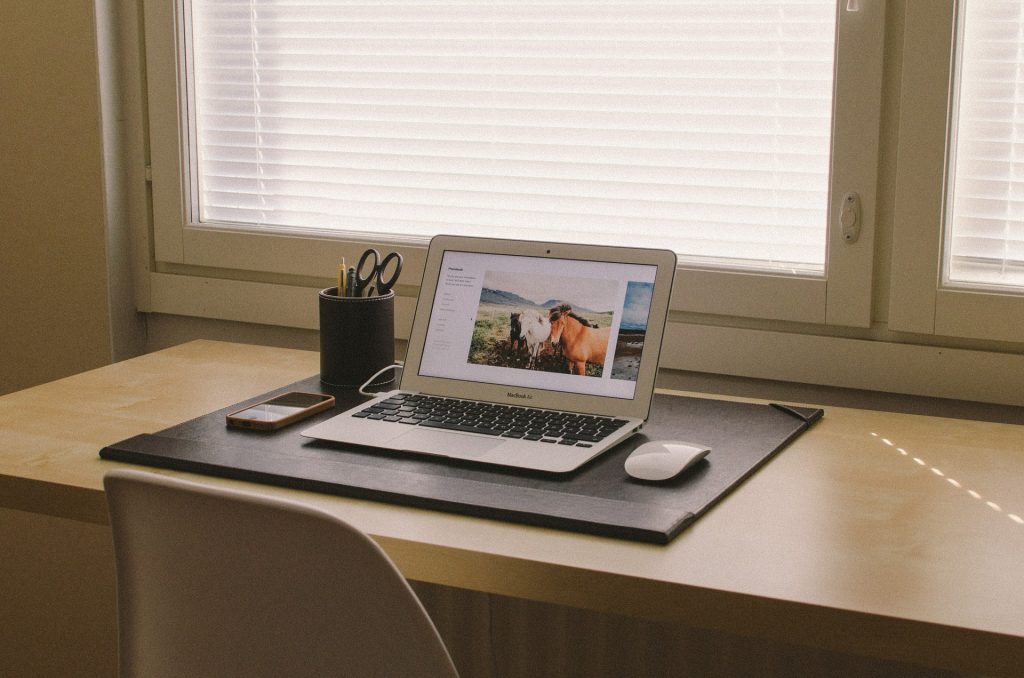 An open laptop sitting on a desk with a window in the background