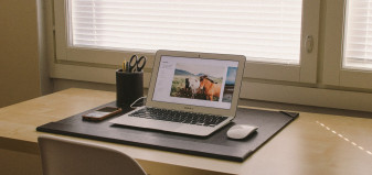 An open laptop sitting on a desk with a window in the background