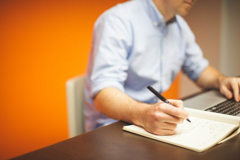 A worker working at a desk with a pad and pen.