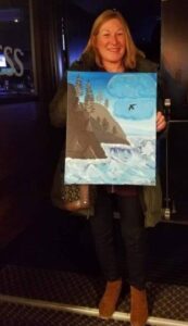 Women holds up painting of mountain and sea