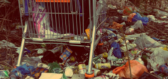 A shopping cart surrounded by rubbish and cans