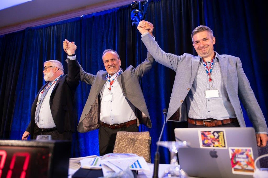 David Black, Minister Harry Bains, and Pierrick Choinière-Lapointe joining hands in the air
