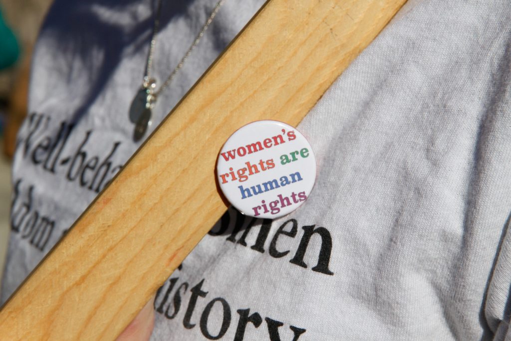 Person wearing button that reads "women's rights are human rights"