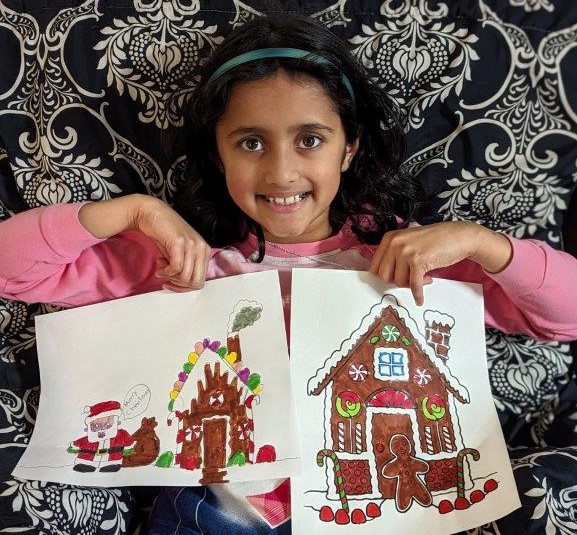 Child holding up two coloured drawings