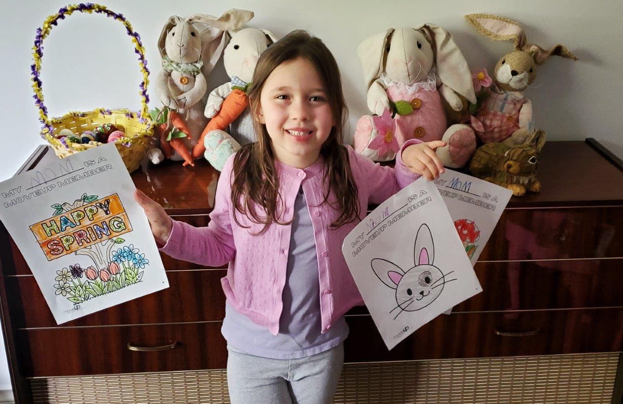 Child holding up coloured drawings