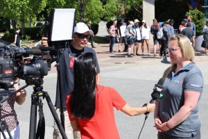 Christy Slusarenko in a gray shirt speaking to a Global reporter in red with a camera operator behind them