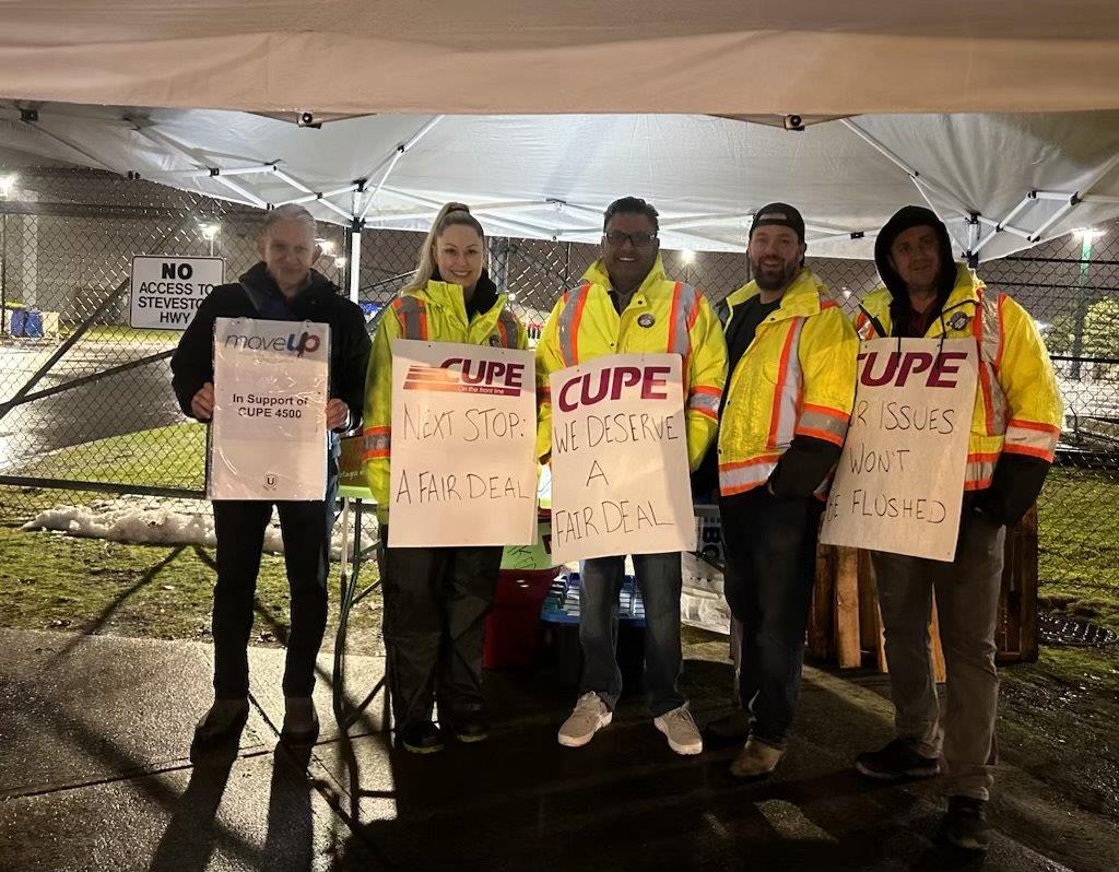 Transit workers standing on a picket line with strike signs