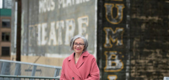 Jennifer Whiteside dressed in pink coat in front of building with the word 