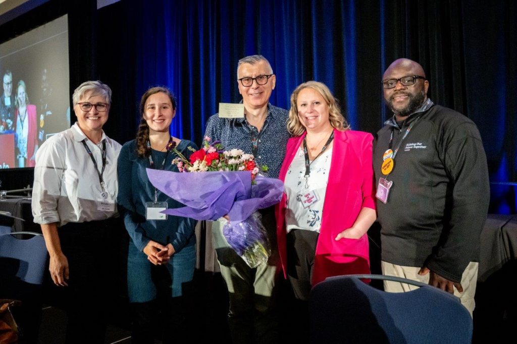 Zoran Stjepanovic (centre), recipient of the Peter Corren Award, poses for a photo after accepting the award with several individuals from MoveUP