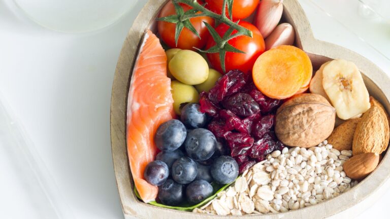 Salmon, berries, tomatoes, and other healthy foods in a heart shaped bowl