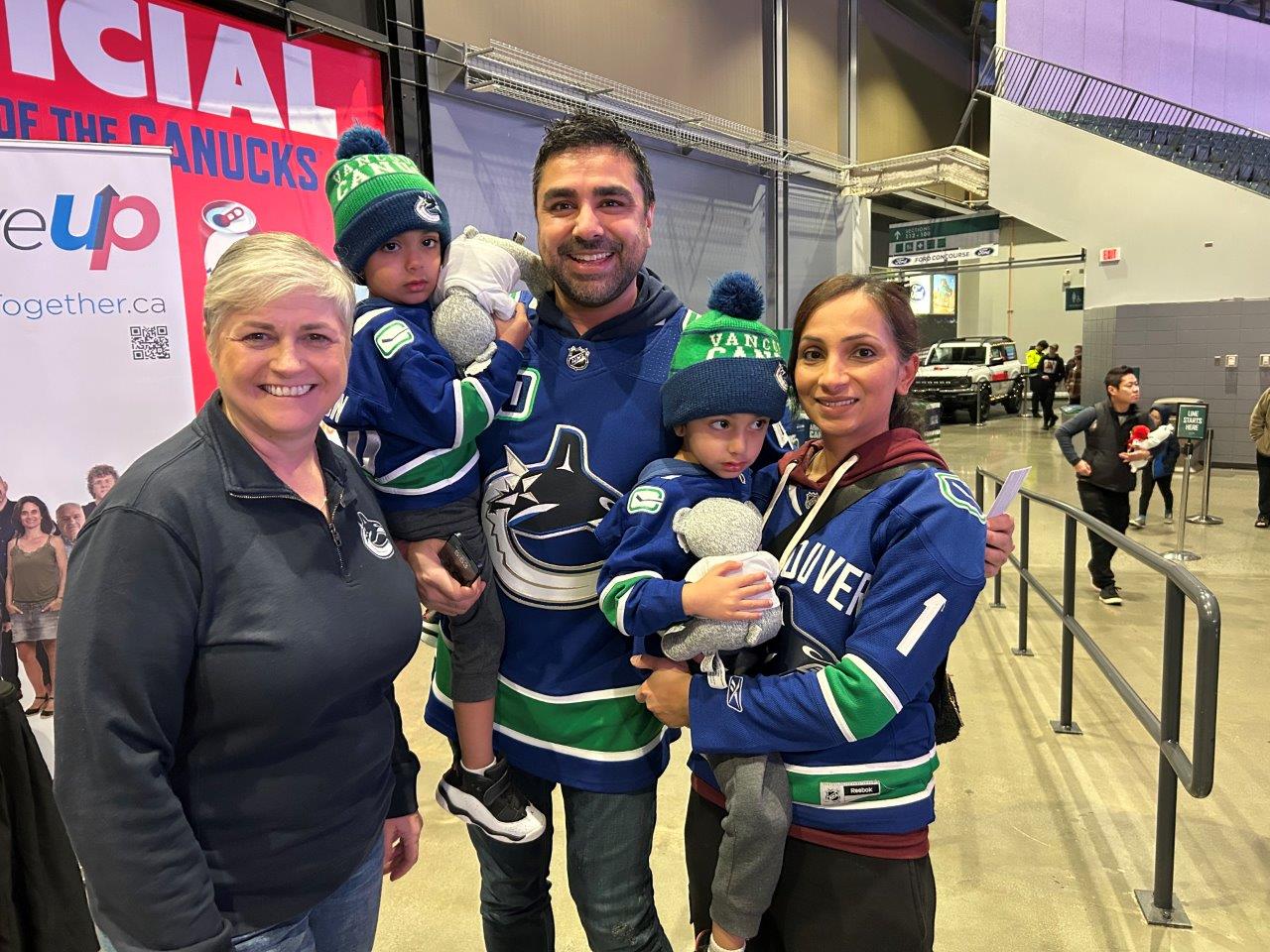 Photo 2024-12-14, 5 53 06 PM MoveUP members and their families wearing Canucks jerseys with MoveUP President Annette Toth
