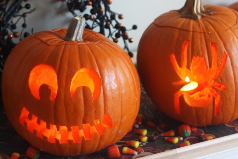 Two jack-o-lanterns, one with a face pattern and the other with a spider pattern, side by side