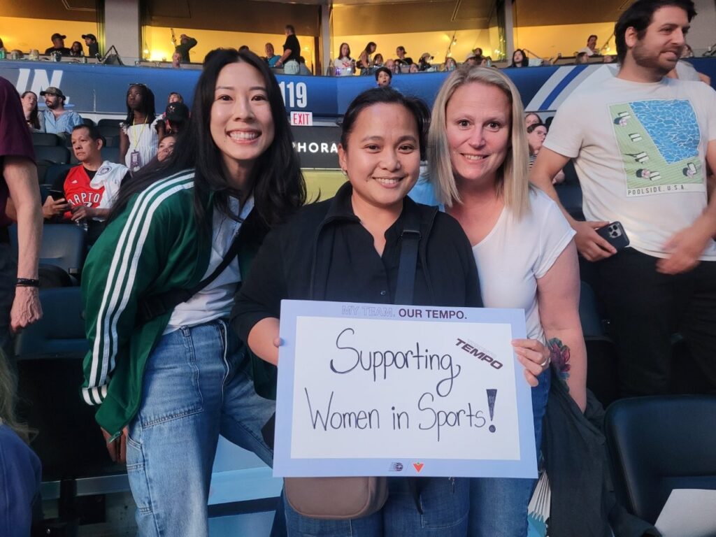 Secretary-Treasurer Brenda Chu and VP Christy Slusarenko and a MoveUP member showing off a sign in support of women's sports