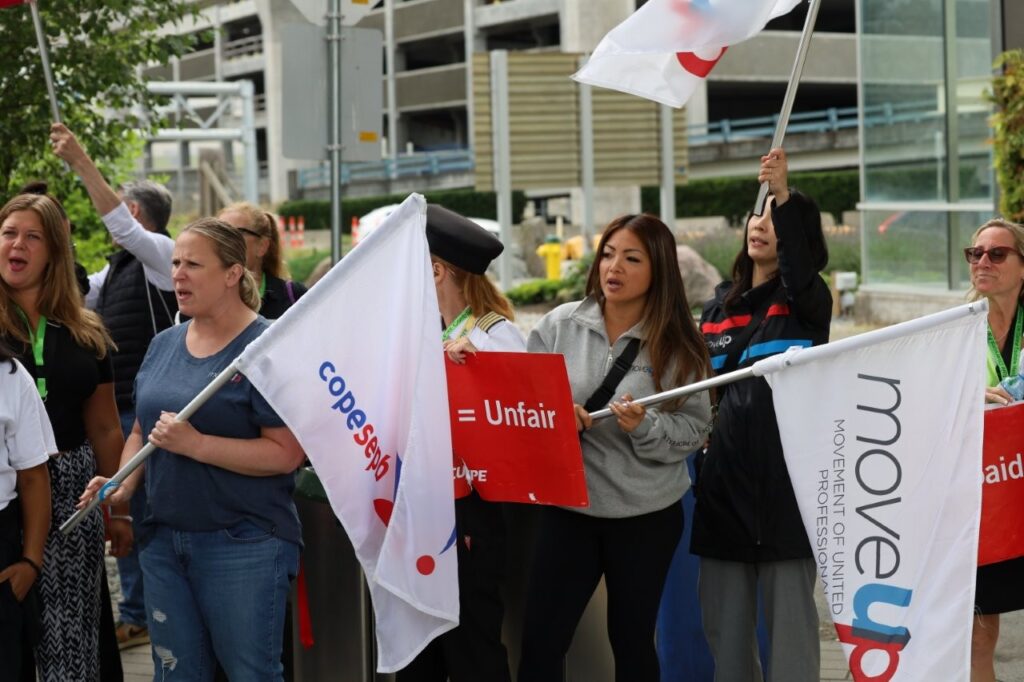 Rallygoers holding COPE and MoveUP flags at an Air Canada strike in August 2025